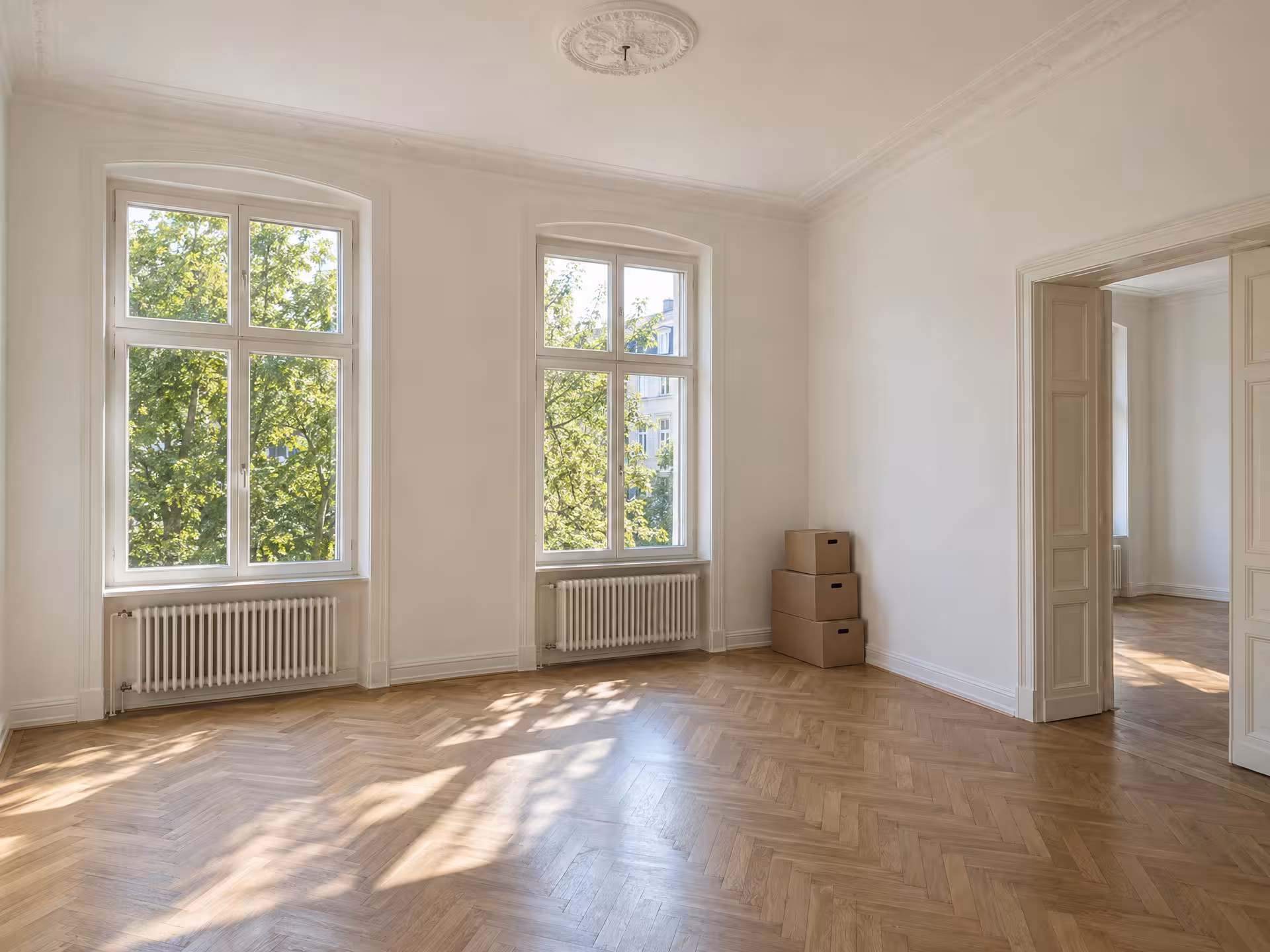 Illustratives Motiv: ein leeres, helles Zimmer einer Altbauwohnung mit Parkett und hohen Fenstern.
