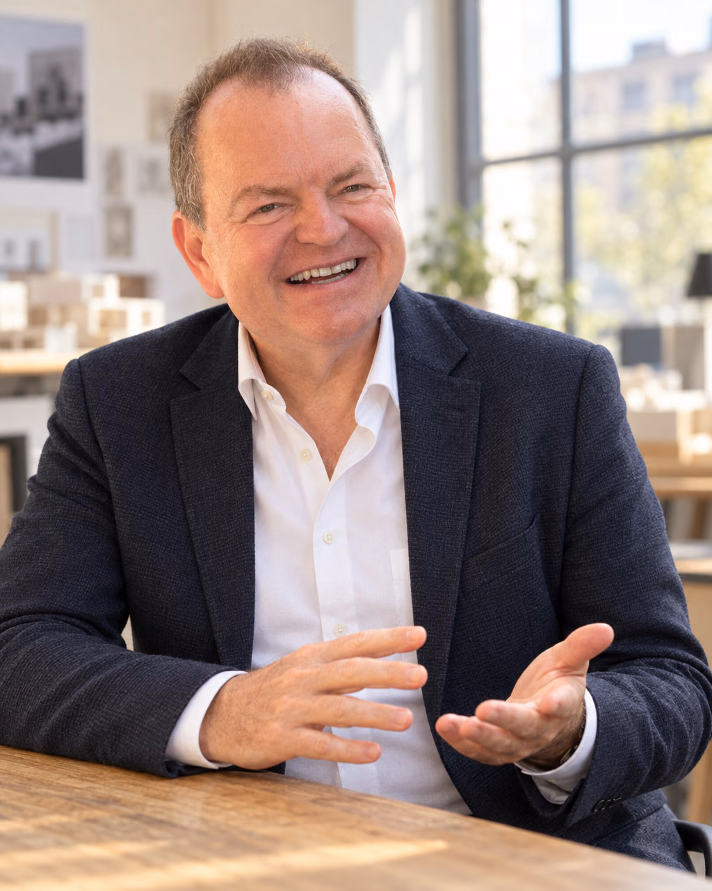 Oliver Preikschat im weißen Hemd und dunkelblauen Sakko im hellen Büro.