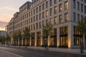 Fassade eines großen Bürohauses mit vielen Fenstern im Abendlicht, davor eine leere Straße.