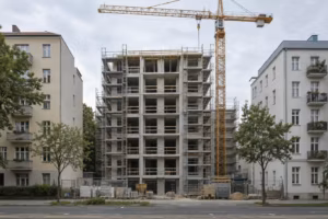 Rohbau eines mehrgeschossigen Wohnhauses mit Gerüst und Baukran zwischen zwei älteren Berliner Wohnhäusern.