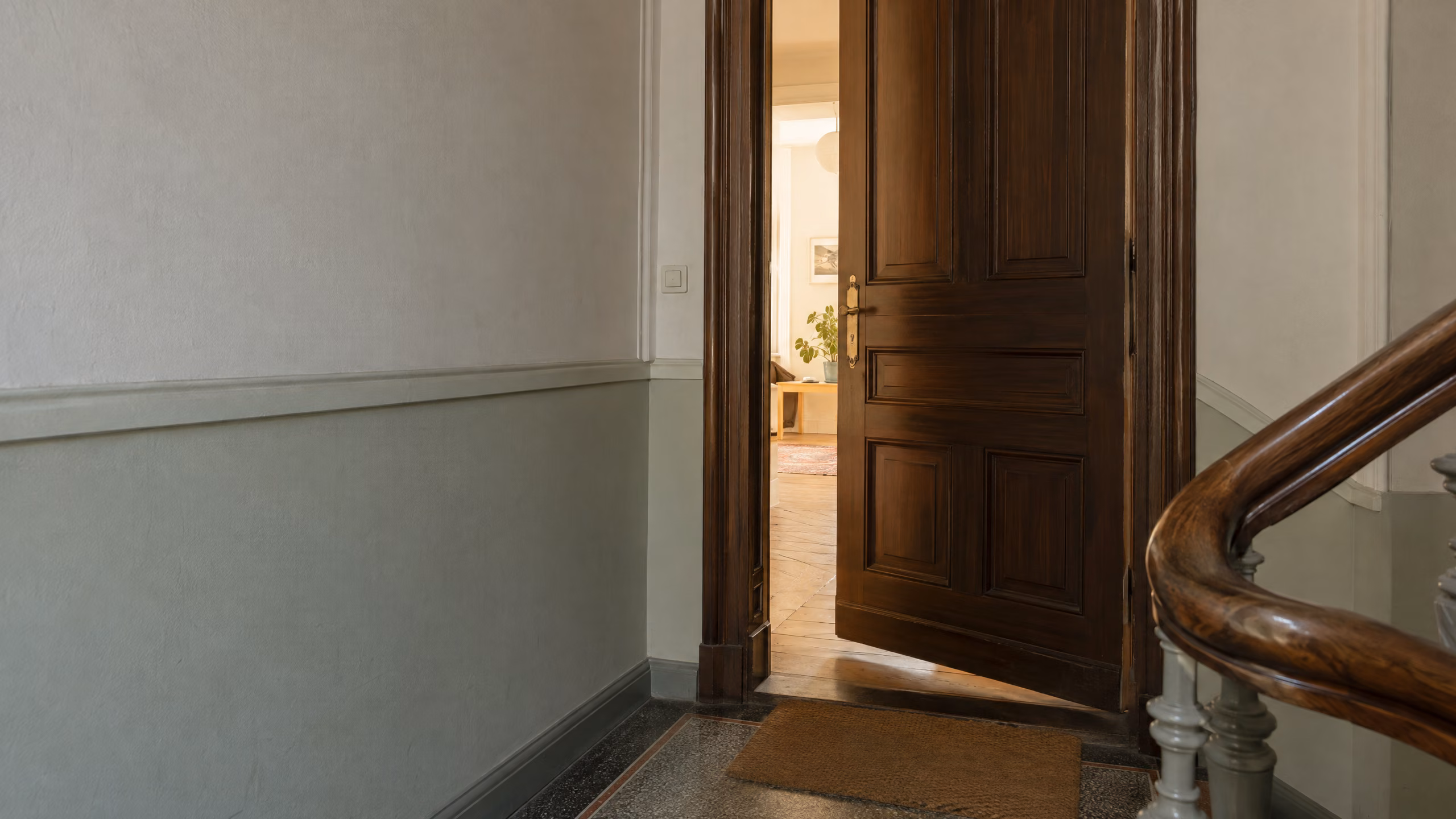 Halb geöffnete hölzerne Wohnungstür in einem Berliner Altbau, aus der Wohnung fällt Tageslicht ins Treppenhaus.
